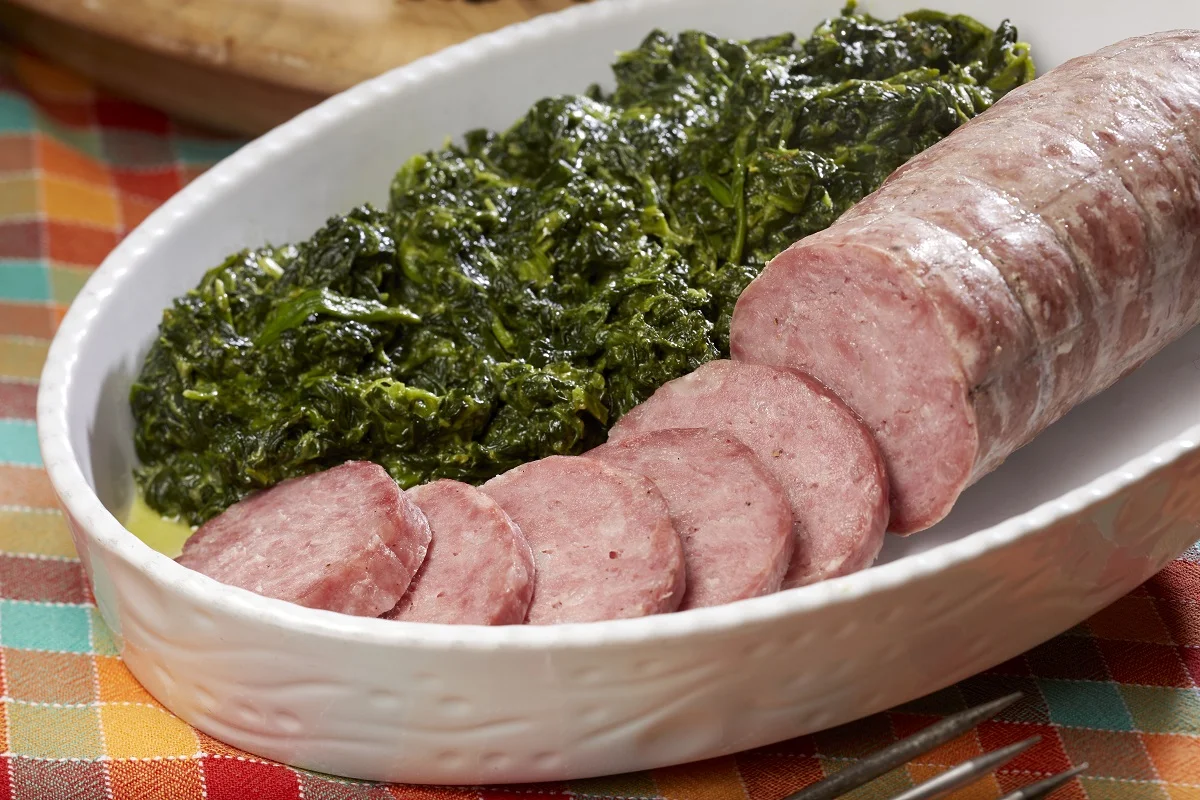 Salame cotto affettato con polenta su un tagliere